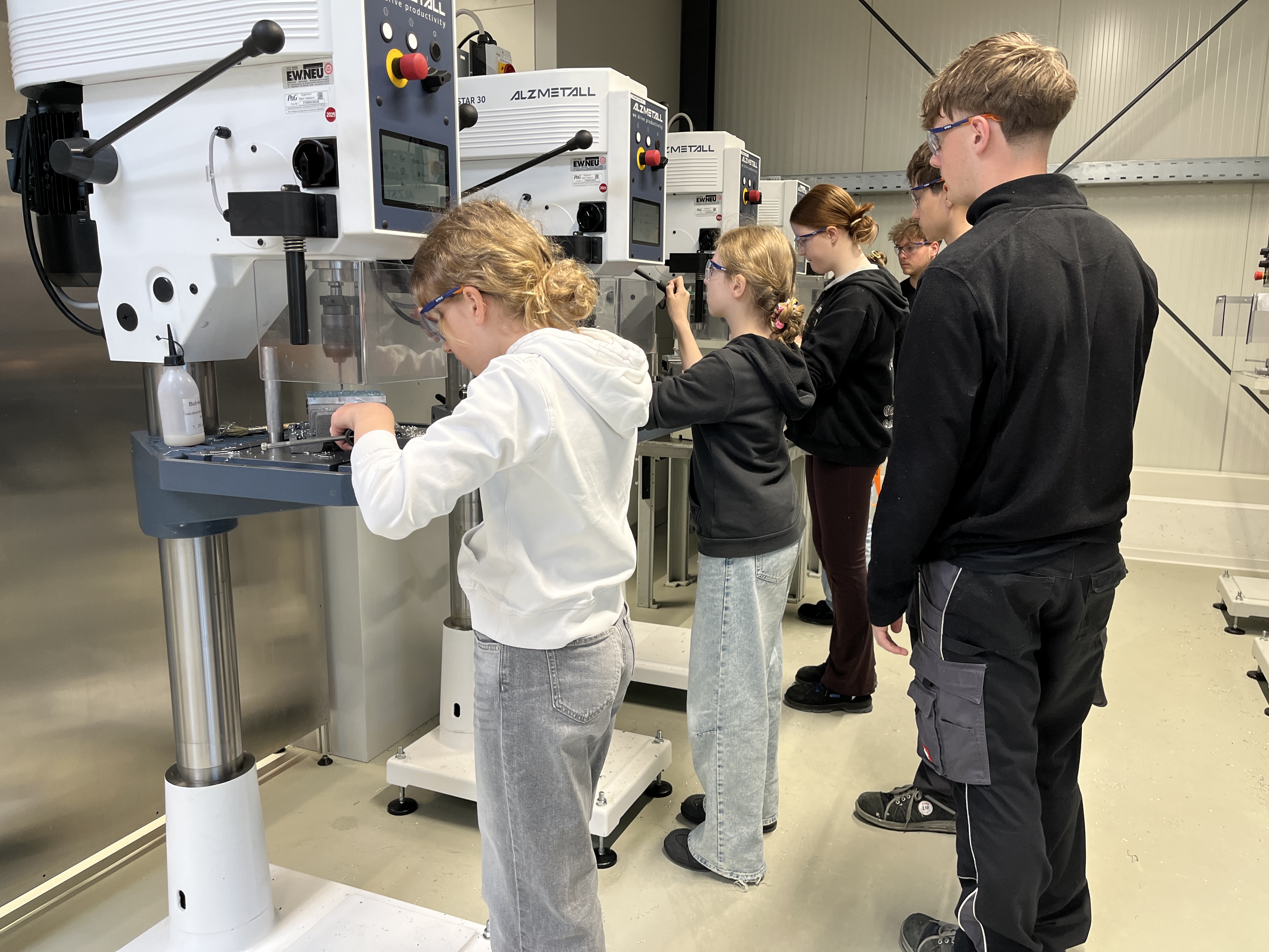 Three girls standing and inspecting the BRAUN razors in our BRAUN plant in Walldürn while being instructed by BRAUN workers.