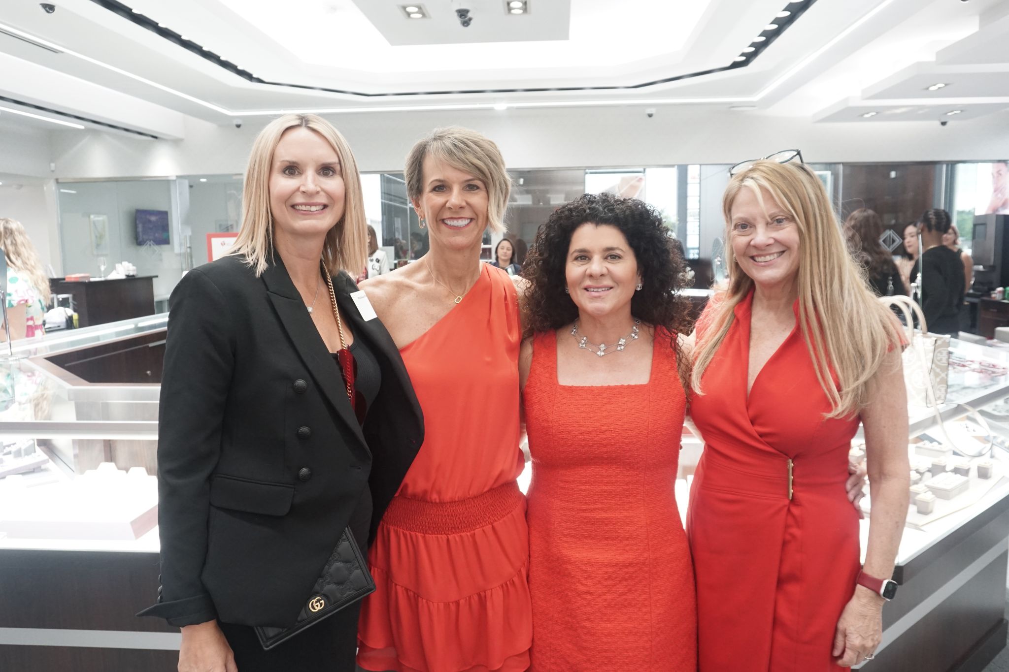 diamonds direct employees wearing red dresses smiling in a jewelry store